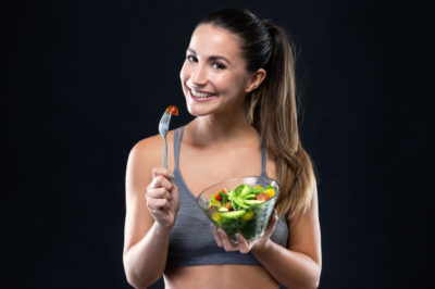 beautiful-young-woman-eating-salad-black-background_1301-7563